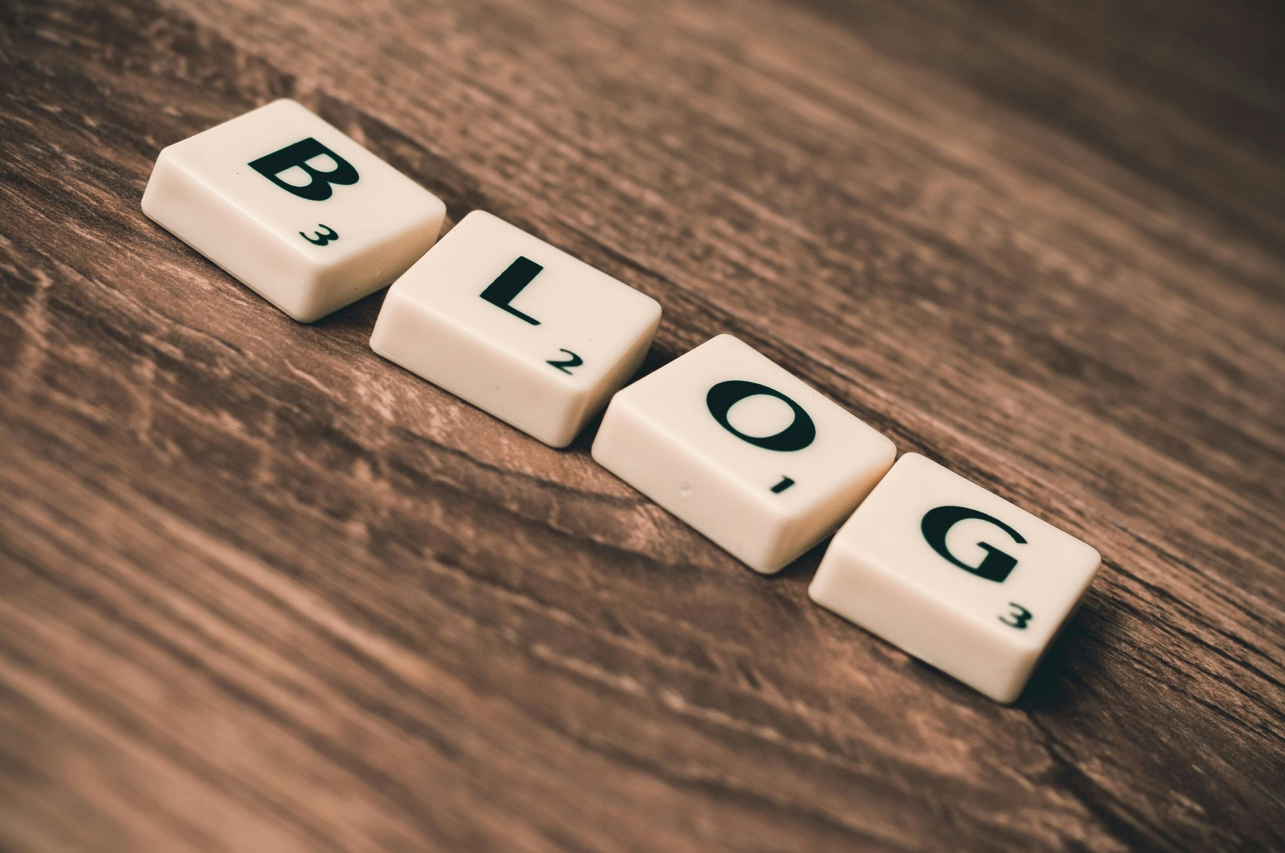 Blogs Scrabble tiles spelling 'BLOG' on a wooden background, symbolizing creativity and writing.